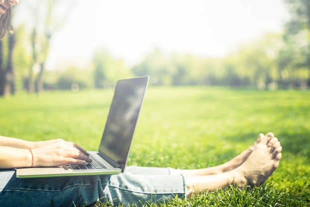 woman sitting in grass on laptop