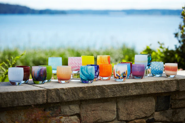Display of Glassybaby candle holders on a brick wall overlooking the ocean.