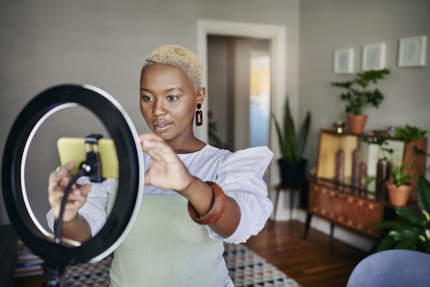  Young entrepreneur adjusting a smart phone and ring light before making a tiktok post