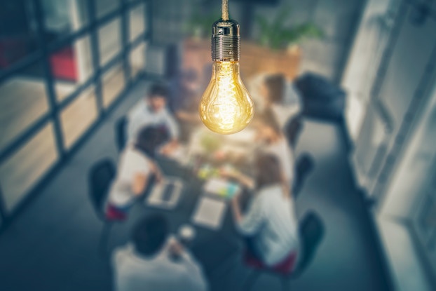  lightbulb with a group of coworkers in a meeting in background