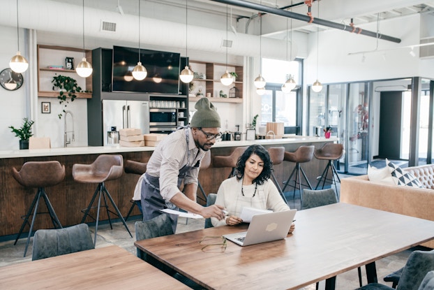  two people inside their business working on a laptop