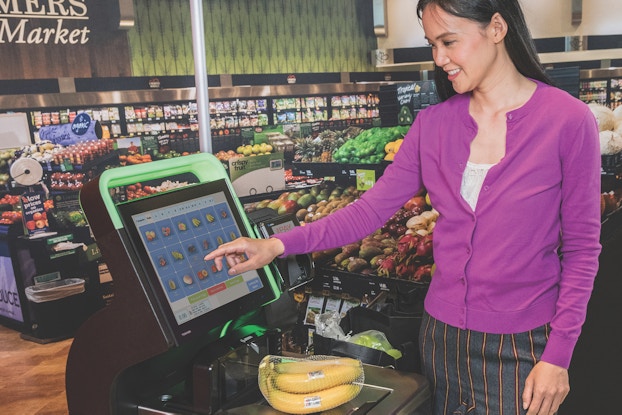 woman using self-checkout in supermarket