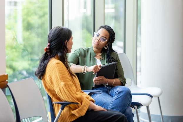  An empathetic woman business owner listens to an employee who is speaking with her in a serious manner.