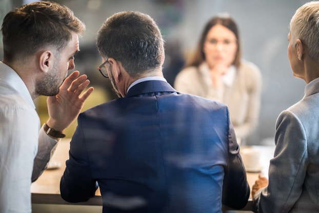 professionals in a meeting whispering