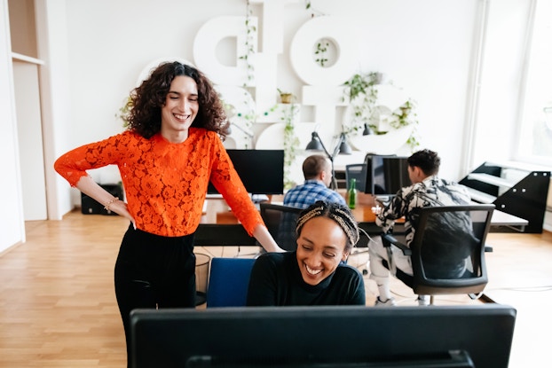  Smiling manager with employee at the office working on a computer.