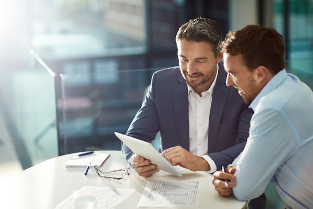  two men in business meeting reviewing paperwork