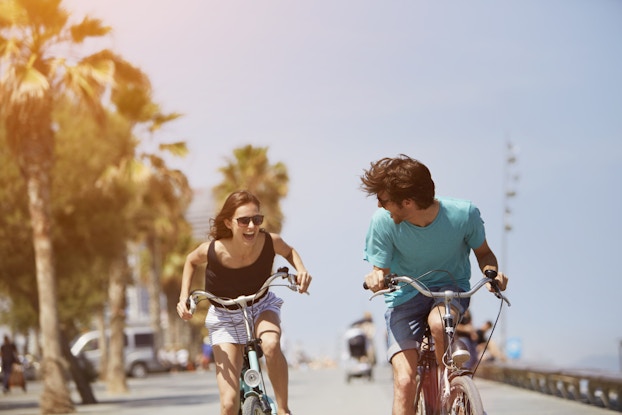  Two happy people smiling and riding bicycles on a sunny day.