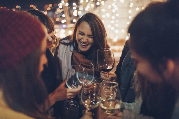  A group of girlfriends laughing and drinking wine together.
