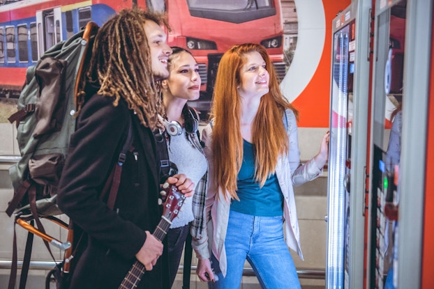  Three people trying to decide what to get from a vending machine.