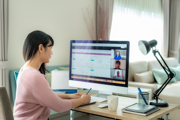 Woman video chats at desk.