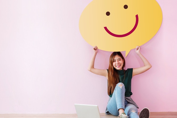 girl sitting on floor holding smile sign