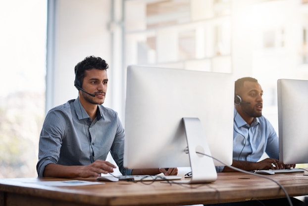 two male co-workers working next to each other on computers