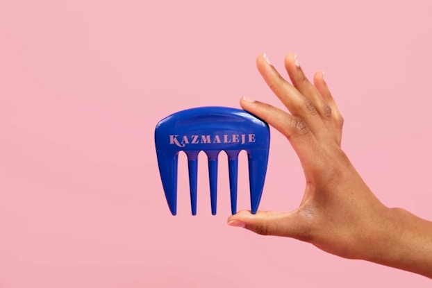Hand holding a blue hairbrush by Kazmaleje.