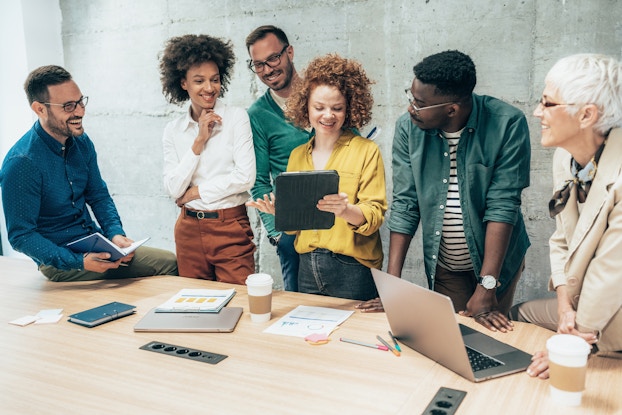  Group of coworkers standing around a table in a team meeting.