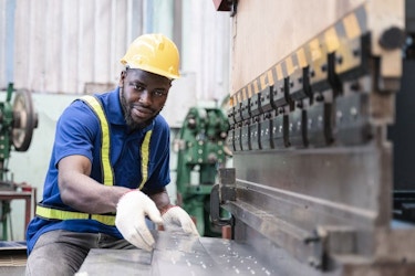 A man works with a steel-cutting machine. He is handling steel plates.