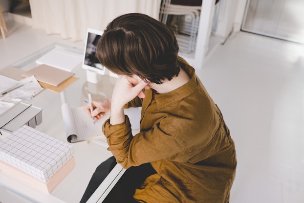 An image of a small business owner seated at a desk writing on a pad of paper.