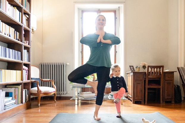  Woman doing yoga with her daughter.