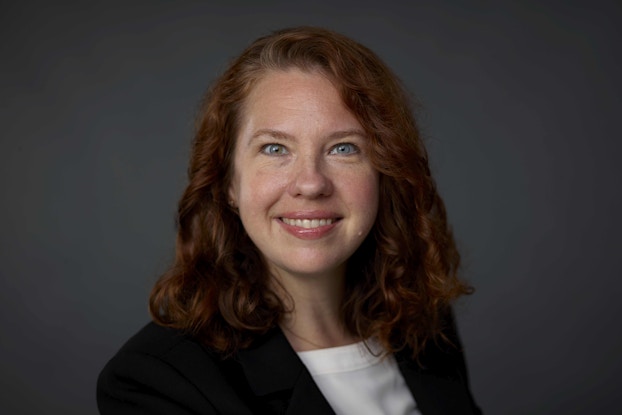 A headshot of Felicia Sinusas, a white woman with shoulder length auburn hair and blue eyes. She is smiling and looking directly at the viewer.