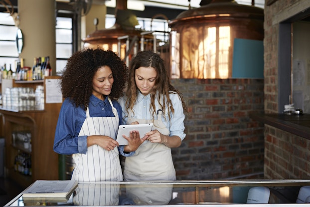 Two co-workers working together on a tablet inside a restaurant.