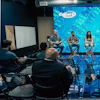 a group of people sitting in chairs in a room with a large screen