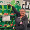 a woman standing next to a shelf of fruit