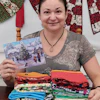 a woman holding a card and a stack of fabric