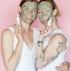 two women with facial masks posing for a picture