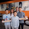 a group of people holding plates of sushi