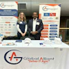 a man and woman standing next to a table with a sign