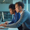 a man and woman looking at computers