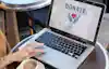 Close-up of a hand using a mouse trackpad on a laptop. The screen displays a Donate icon.